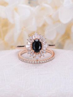 an engagement ring set with a black diamond surrounded by white and rose gold diamonds on a table