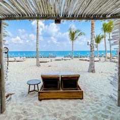 the beach is lined with palm trees and lounge chairs under a pergolated roof