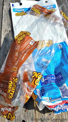 three bags of snacks sitting on top of a wooden table next to an orange and blue bag