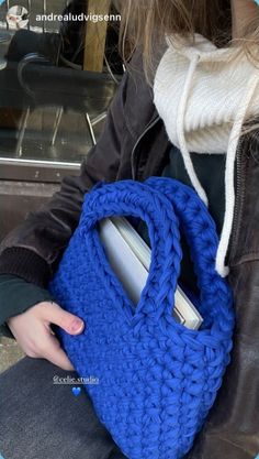 a woman holding a blue crocheted purse