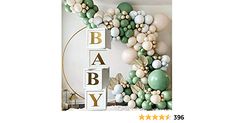 a baby shower decoration with balloons and greenery on the wall in front of it