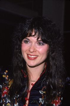 a woman with long black hair smiling at the camera