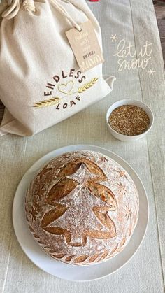 a loaf of bread sitting on top of a white plate next to a bag and two bowls