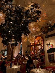 people sitting at tables in a fancy restaurant with chandeliers hanging from the ceiling