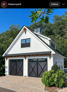 a white house with black garage doors and windows