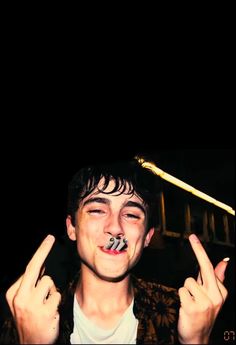 a young man is making the peace sign with his fingers while standing in front of a black background