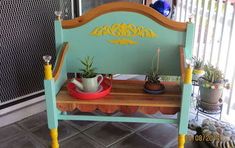 a teal bench with potted plants on it and a yellow trim around the seat