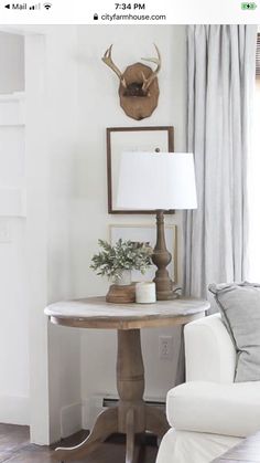 a living room with a couch, table and deer head on the wall above it