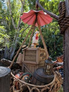 a chicken sitting on top of a wooden box in the middle of ropes and rope