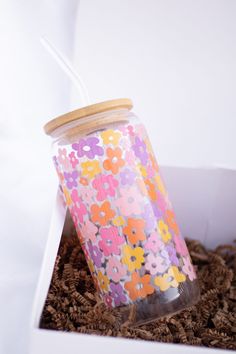 a cup with a straw in it sitting inside of a cardboard box filled with flowers