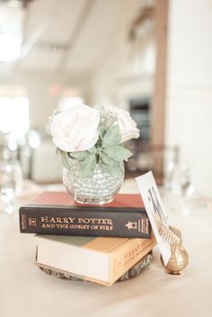 two harry potter books on top of each other with a flower in a glass vase