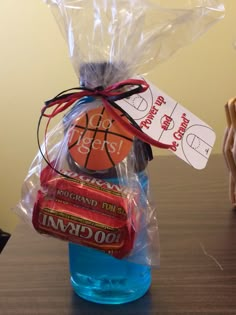 a plastic bag filled with candy and basketballs on top of a wooden table next to a bottle of water