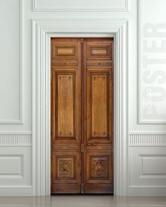 an empty room with two wooden doors and white walls, in the middle of it