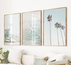 three framed pictures hang on the wall above a couch in a living room with white furniture