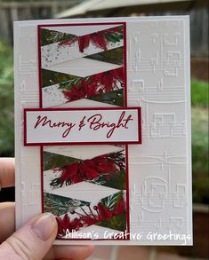 a hand holding up a christmas card with red and green leaves on it, which reads merry & bright