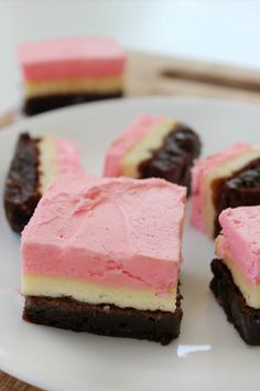 four pieces of cake on a plate with pink frosting and chocolate in the middle