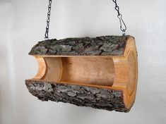 a bird feeder made out of wood and chains hanging from the side of a wall