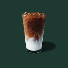 a glass filled with liquid and topped with ice cream on a dark green background,