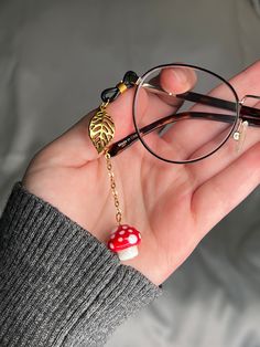 Beautiful mushroom glasses charm: red and white glass mushroom bead on gold-tone chain, with matching metal gold leaf charm.  Single piece made to add to one arm of your glasses.  Silicone loop allows it to easily be added and removed from your glasses to instantly upgrade any outfit! Also available as a full chain: https://www.etsy.com/listing/1370319289/ Approximate chain length: 2 inches. Eye Glasses Accessories, Cute Glasses Accessories, Glasses Accessories Jewelry, Beads Glasses, Mushroom Accessories Aesthetic, Fairy Glasses, Chain For Glasses, Diy Chain Accessories, Glasses Jewelry