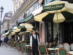 a man standing in front of a restaurant with tables and chairs