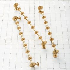 two brass balls are attached to a chain on a white tile floor with grouting