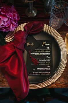 a plate with a menu on it sitting next to a red napkin and some flowers