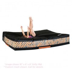 a woman laying on top of a black and orange mattress with her legs in the air