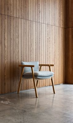 a chair sitting in front of a wall with wood paneling on the walls behind it