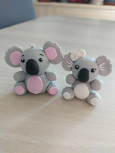 two toy koalas sitting on top of a wooden table