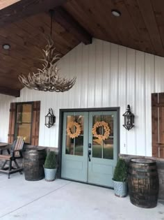 the front door of a white building with two wreaths on it's windows