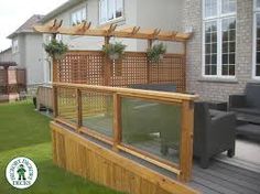 a wooden deck with plants on it next to a house