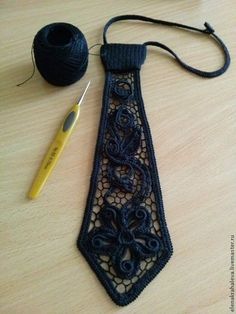 a crocheted neck tie next to a ball of yarn and a knitting needle