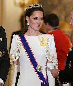 the royal couple are all smiles as they walk down the hall together, wearing tiaras and gowns