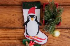 a christmas stocking with a penguin on it next to a pine tree and other decorations