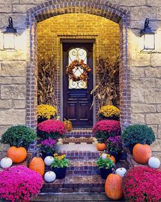 the front door is decorated with pumpkins and flowers