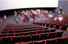 people are walking around in an empty auditorium with black seats and red trimmings