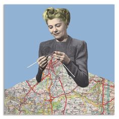 a woman sitting on top of a map holding a knitting needle and needles in her hands