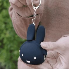 a person holding a keychain with a small animal on it's side