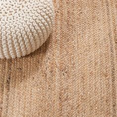 a close up view of a beige rug with a white pillow on the floor next to it