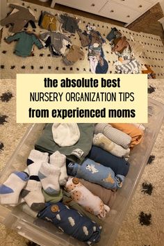 a plastic container filled with lots of baby clothes on top of a carpeted floor