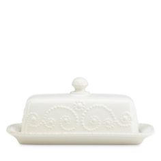 a white cake dish with an ornate design on the front and bottom, sitting on a white surface