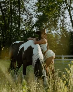 a woman in white dress standing next to a brown and white horse