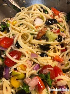 a close up of a pasta salad with olives, tomatoes, and other vegetables