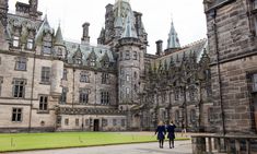 two people walking in front of an old castle