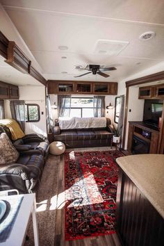 a living room with couches and a television inside of a recreational vehicle that is parked in a lot