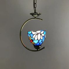 a stained glass light hanging from a metal hook