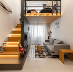 a living room with stairs leading up to the top floor and a couch in front of it