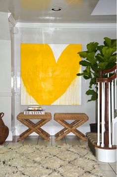 a living room with two chairs and a painting on the wall above it, in front of a staircase