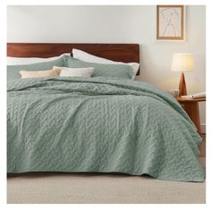 a bed with green bedspread and pillows