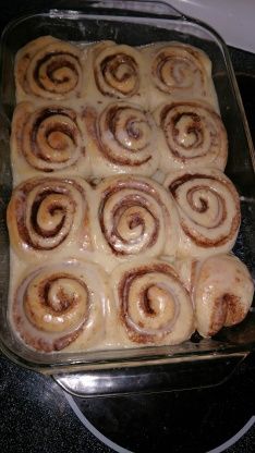 a pan filled with cinnamon rolls sitting on top of a stove